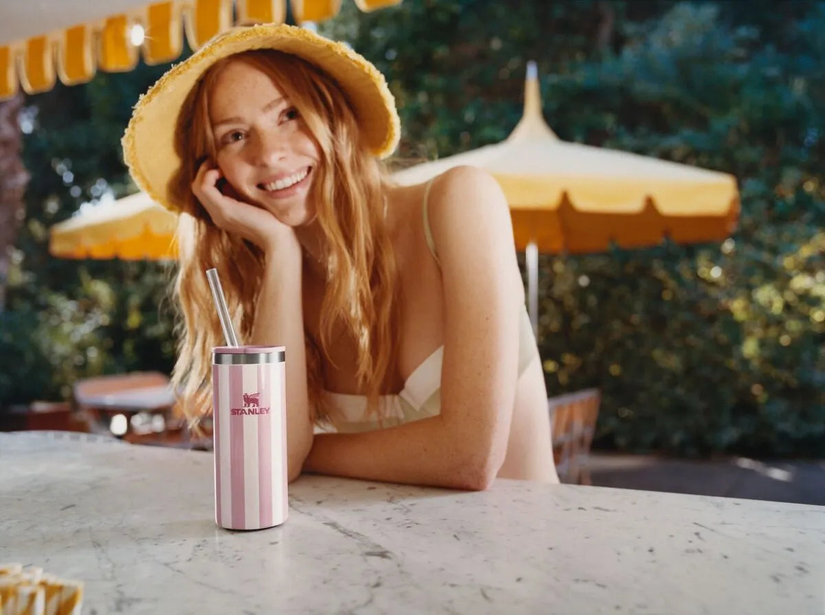 Uma mulher sentada em uma mesa, aproveitando o começo da primavera curtir coquetéis refrescantes com produtos Stanley.