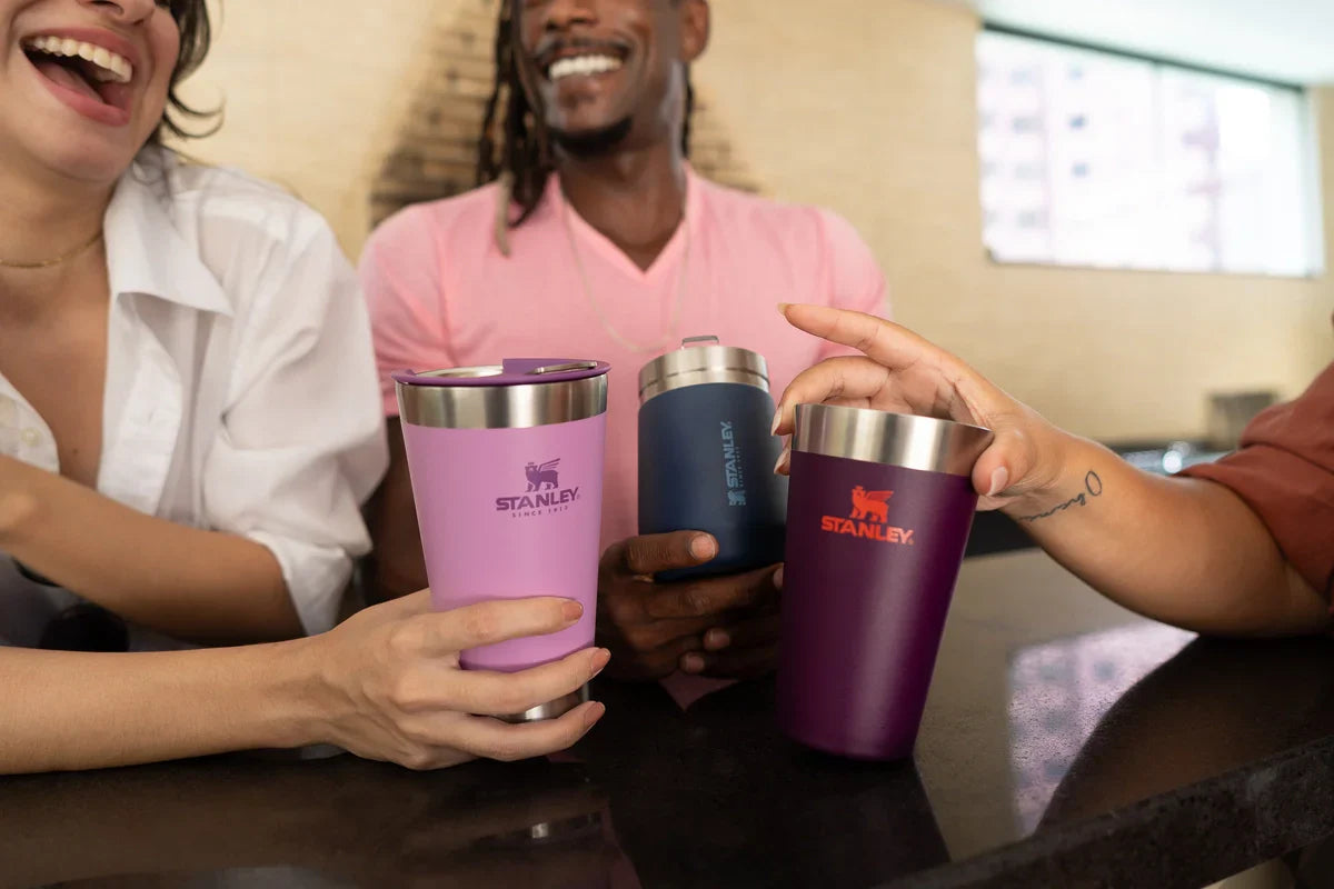 Três amigos brindando ao saber se copo Stanley pode ir na lava-louça.