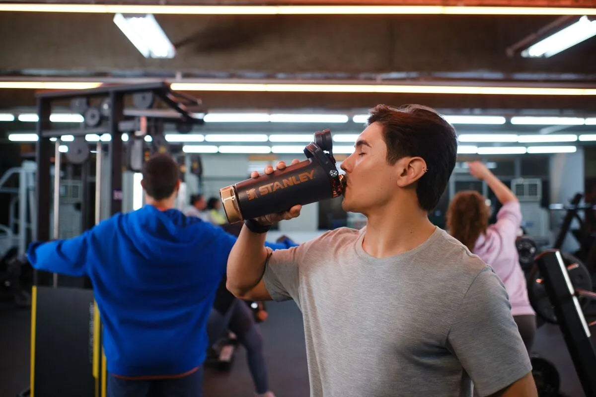 Um homem usando o Vitalize Shaker Stanley para se hidratar durante os exercícios na academia.