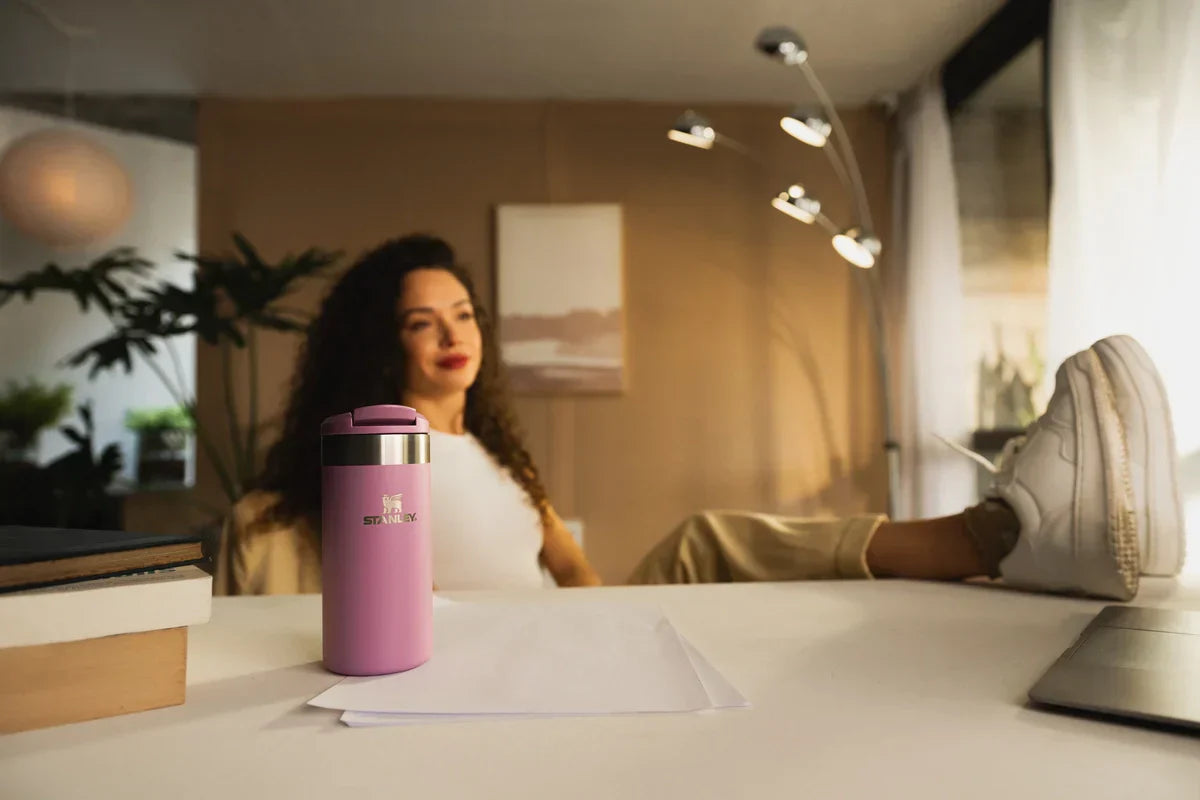 Uma mulher aproveitando a nova garrafa Aerolight Transit que faz parte da linha Café Stanley.