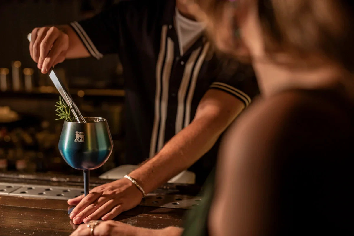 Uma pessoa fazendo um drink em um Cocktail Glass enquanto outra foi servida em um copo de cerveja.