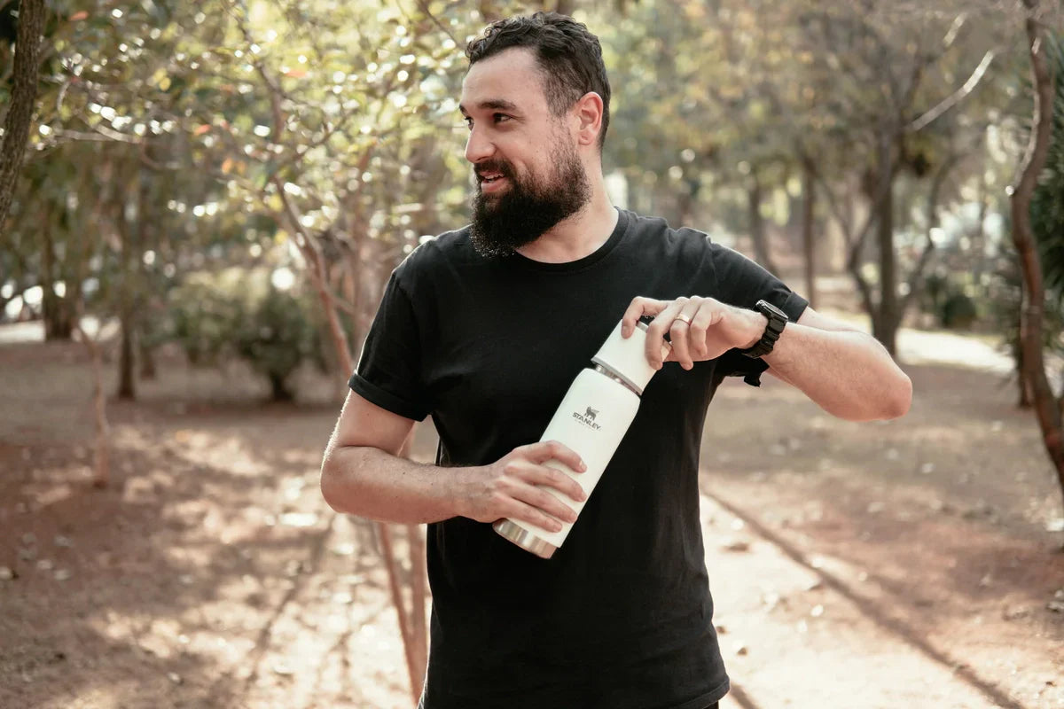 Um homem segurando a sua garrafa, sabendo que pode colocar café na garrafa Stanley.
