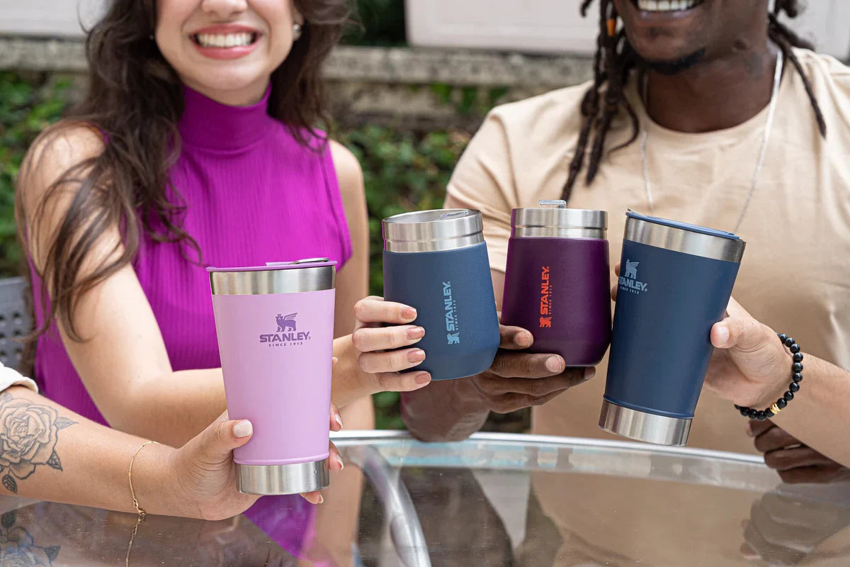 Quatro pessoas brindando com os copo Stanley, felizes e sorrindo por saberem qual o segredo do copo Stanley.