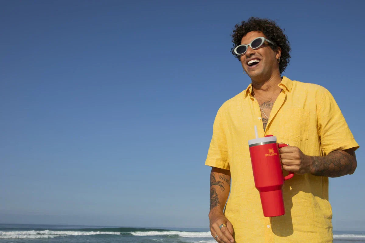 Um homem usando um copo Quencher Stanley para ter mais praticidade no dia a dia.